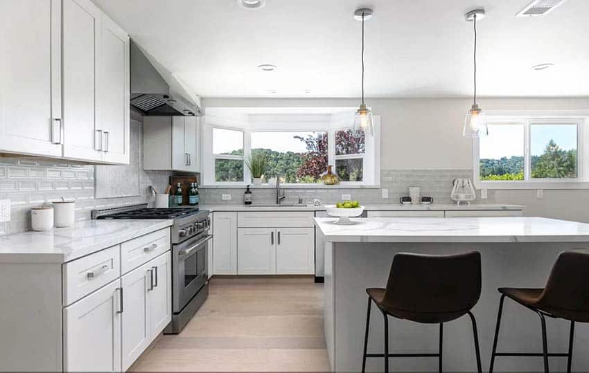 Remodeled kitchen with white cabinets, gray island and tile backsplash