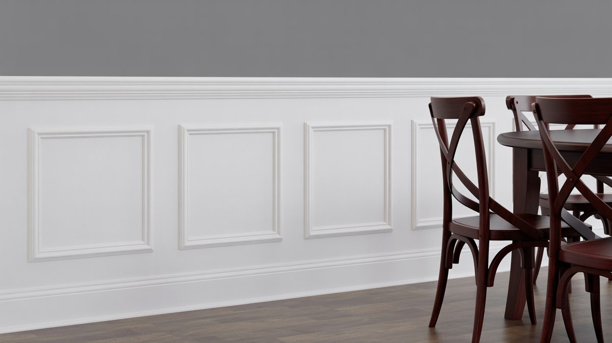 Close-up of white raised square panel wainscoting with bold crown molding cap rail beside cross-back dark wood dining chairs