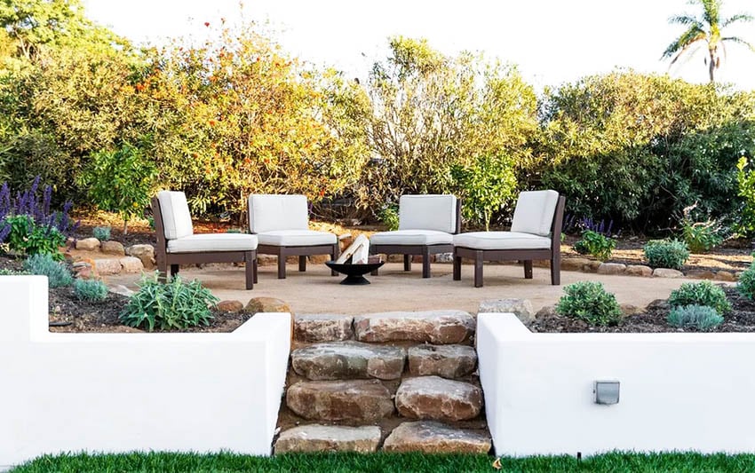 Backyard gravel patio with outdoor furniture and small metal fire pit