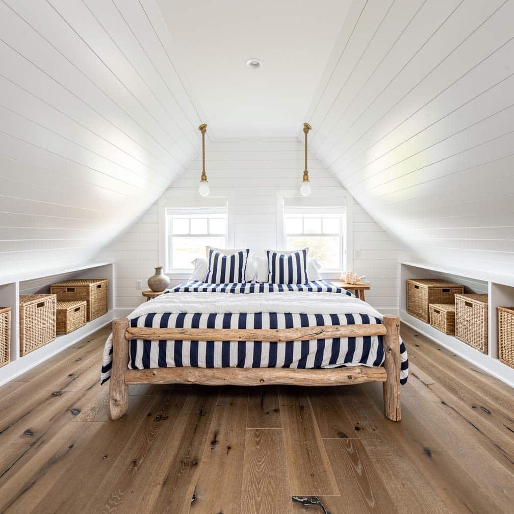 Coastal attic bedroom with white shiplap walls, driftwood accents, and navy striped bedding