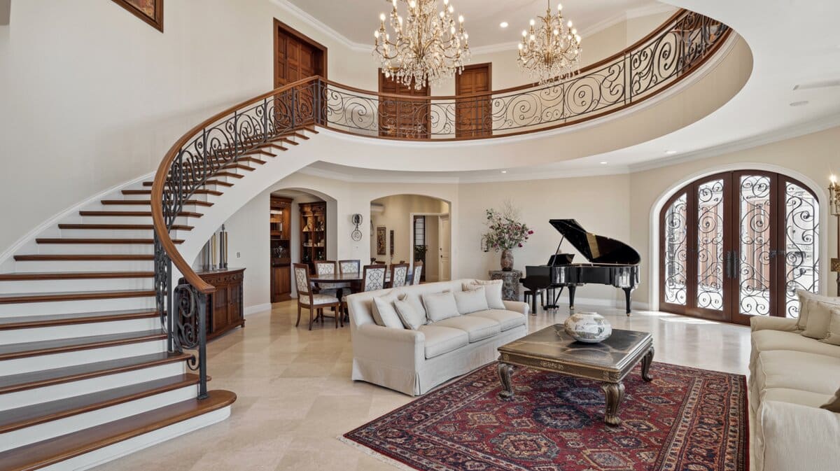 Expansive Mediterranean great room with double-height curved wrought iron railing and travertine floor