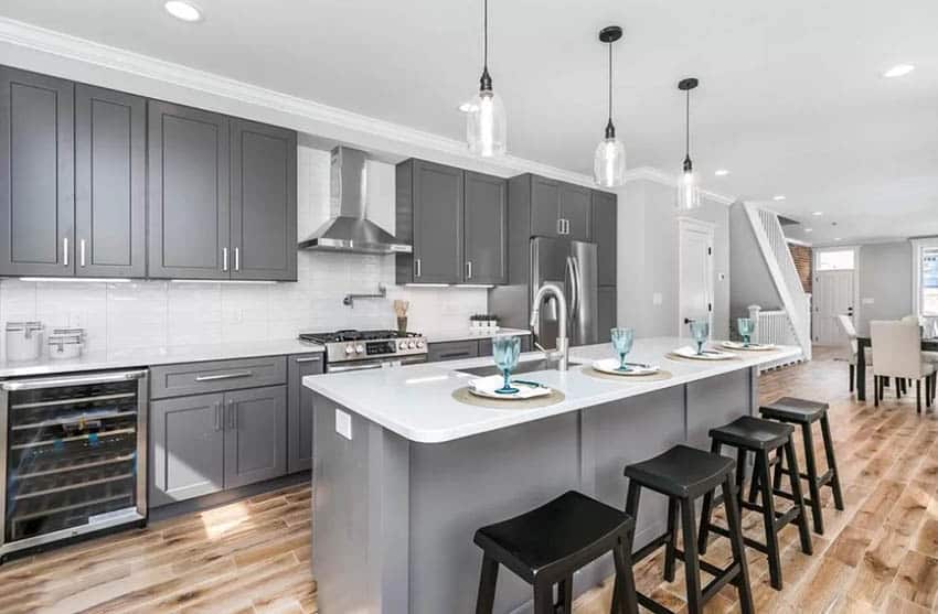 Gray kitchen cabinets with white quartz countertops and white tile backsplash