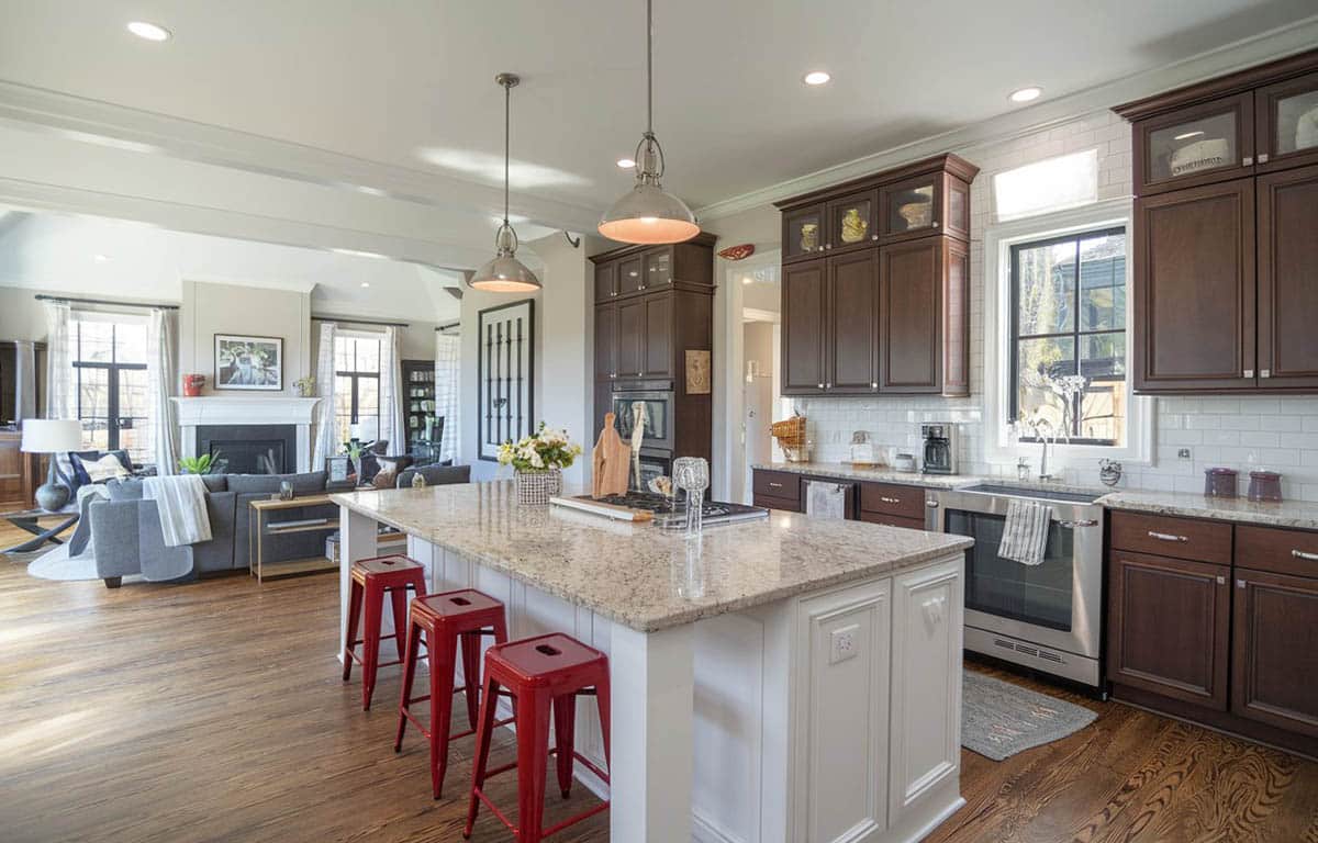 Kitchen with three red stools, two tone cabinetry and tile backsplash