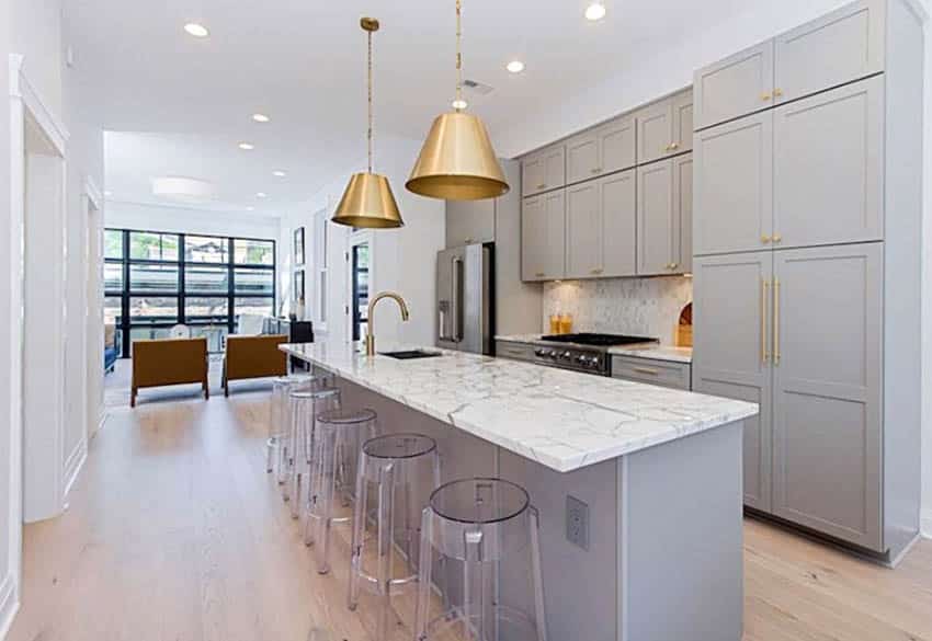 Kitchen with light gray cabinets, gold door hardware and quartz countertops