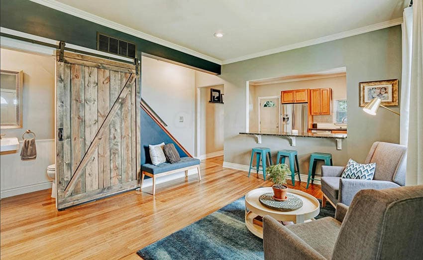 Room with blue green rug, wooden floors and brigh green stools