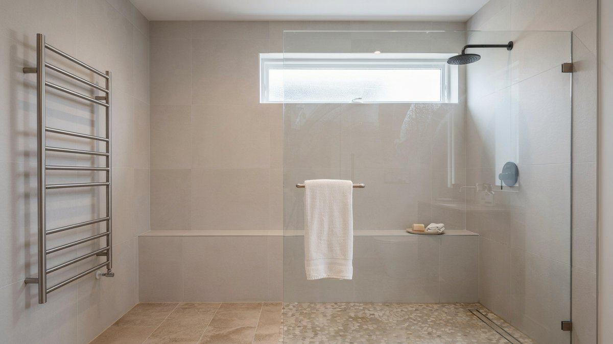 Heated towel rack on the wall just outside a frameless glass walk in shower