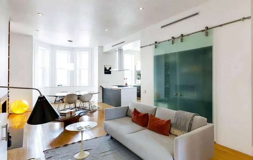 Door made of glass with brushed steel barn door hardware, love seat and dining table