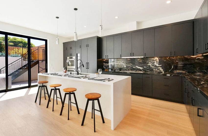 Modern kitchen with dark gray cabinets and white island with light wood flooring