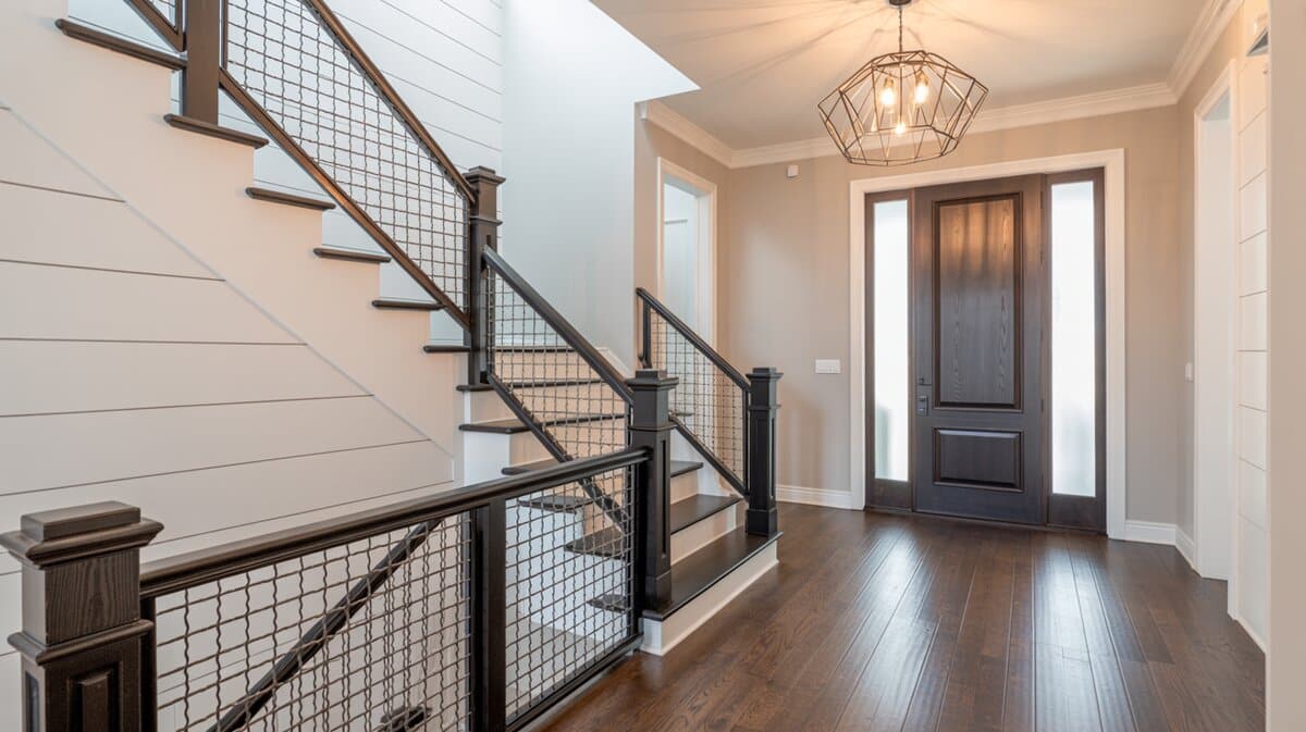 Modern transitional foyer staircase with black cable wire railing and dark wood with geometric chandelier
