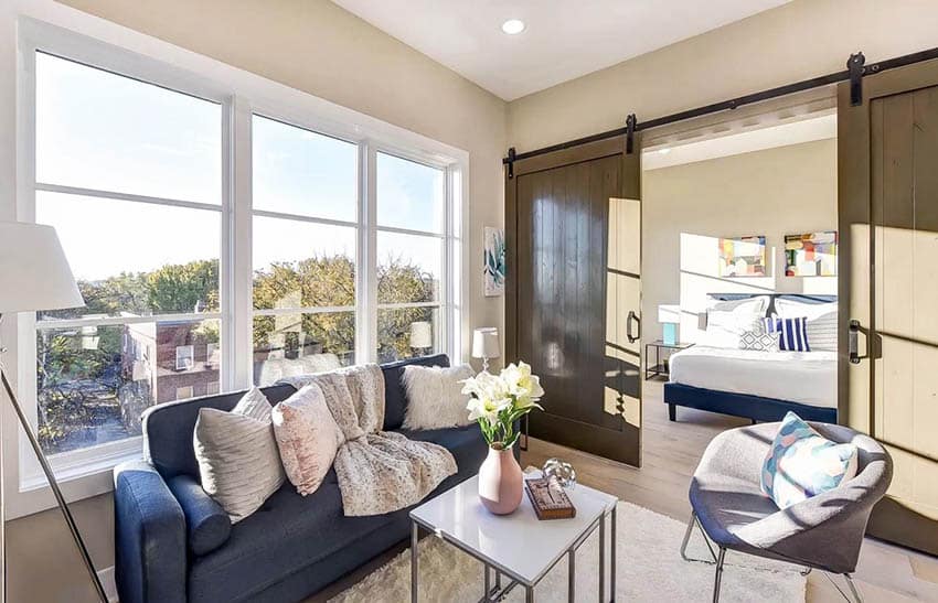 Blue couch with cushions, panel windows and view of the bedroom