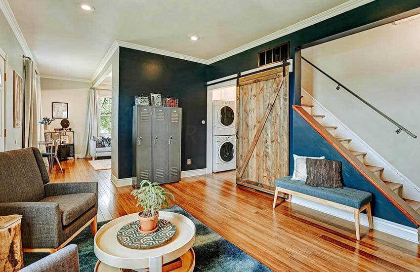 Room with dark gren divider, stairs with glass railings and steel cabinets