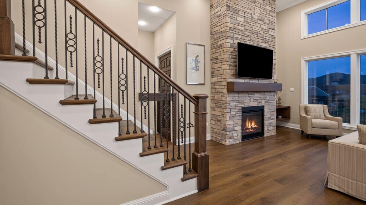 Two-story contemporary living room staircase with wrought iron balusters and stone fireplace mountain view