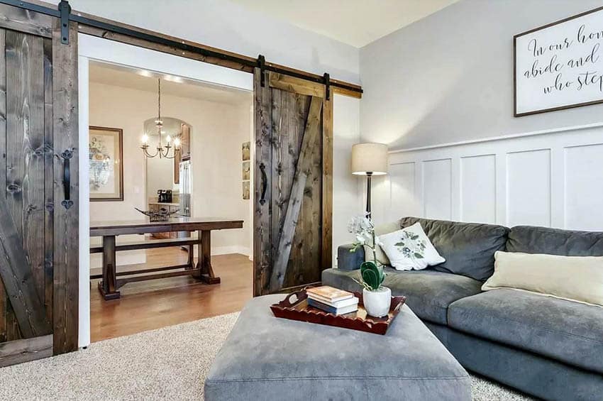 Wooden door, velvet couch, wainscot and light gray walls