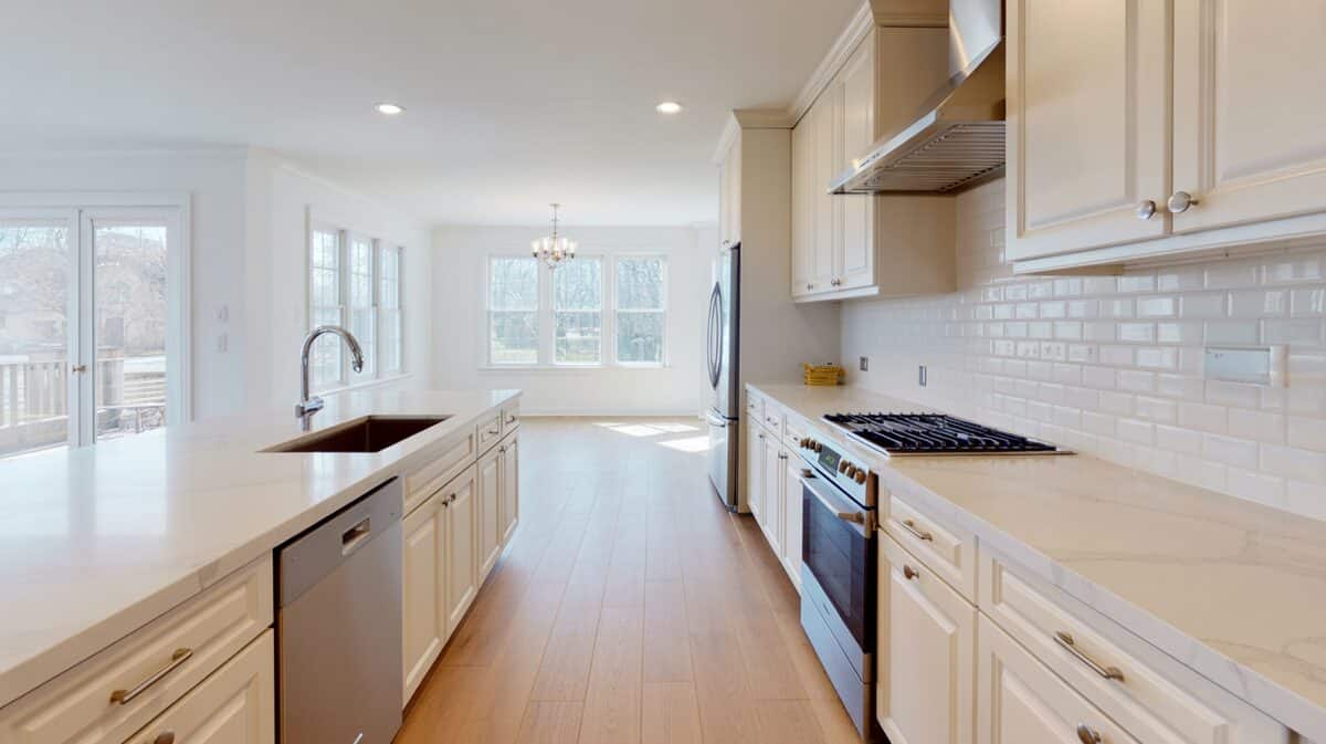 Airy white Cambria quartz counters running along a bright cream cabinet kitchen