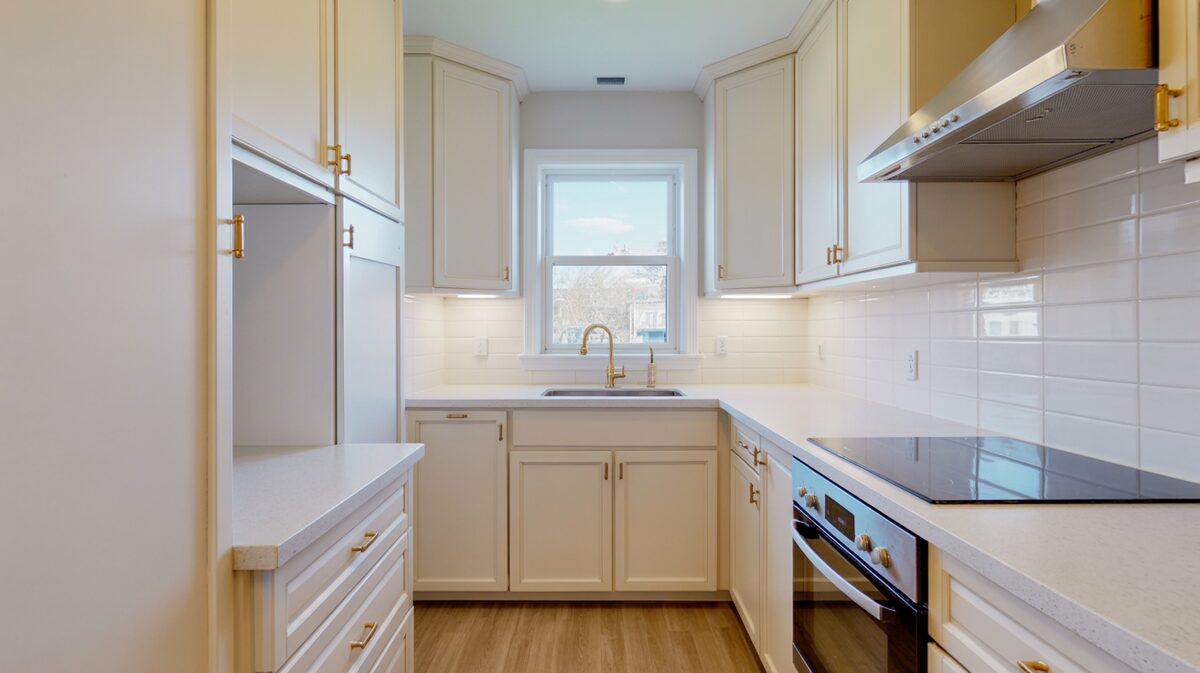 Small white kitchen with gold hardware and pale Cambria quartz countertops
