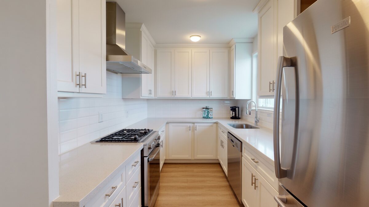 Compact white galley kitchen lined with speckled Cambria quartz countertops