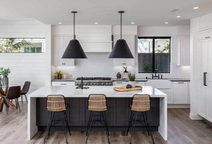 Black and white kitchen with white cabinets, black island and black lamp shades