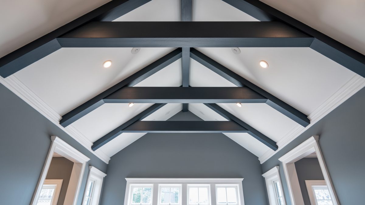 Charcoal painted beams crisscrossing a white vaulted ceiling above gray walls and white trimmed windows