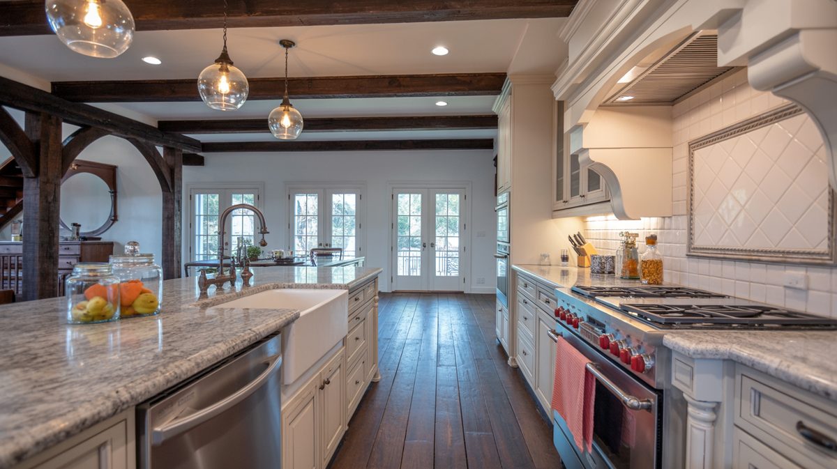 Kitchen island with glass globe pendants below dark ceiling timbers, granite counters, and an apron front farmhouse sink