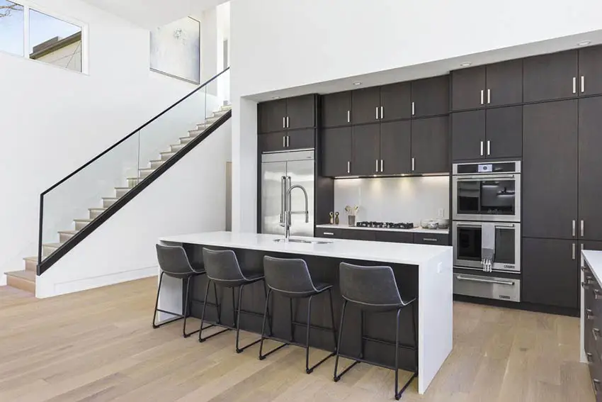 Modern kitchen with black cabinets white quartz counters wood flooring