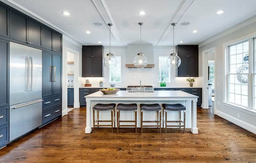 Open concept kitchen with black cabinets white island and white tile backsplash