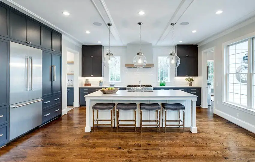 Open concept kitchen with black cabinets white island and white tile backsplash