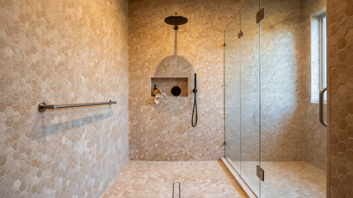 Shower with penny tiles covering both the walls and floor in warm neutral tones