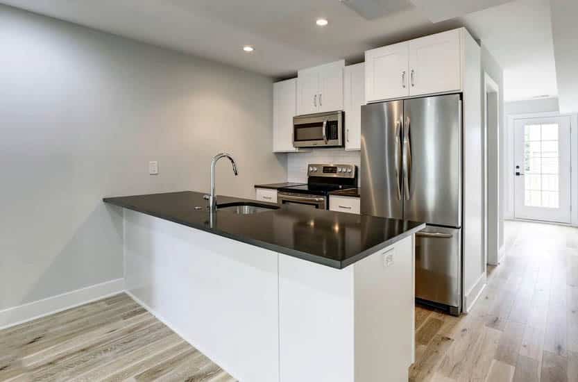 Small kitchen with white cabinets black countertops white subway tile backsplash and peninsula