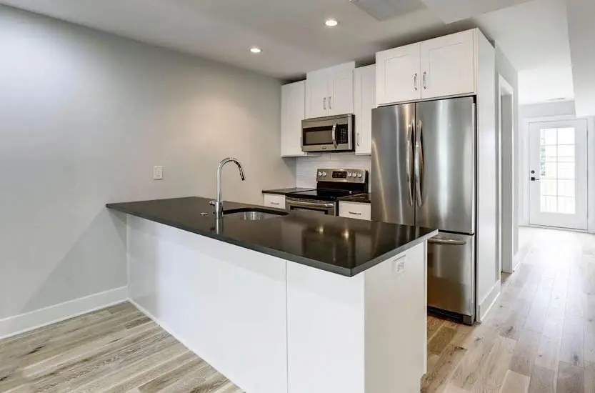Small kitchen with white cabinets black countertops white subway tile backsplash and peninsula