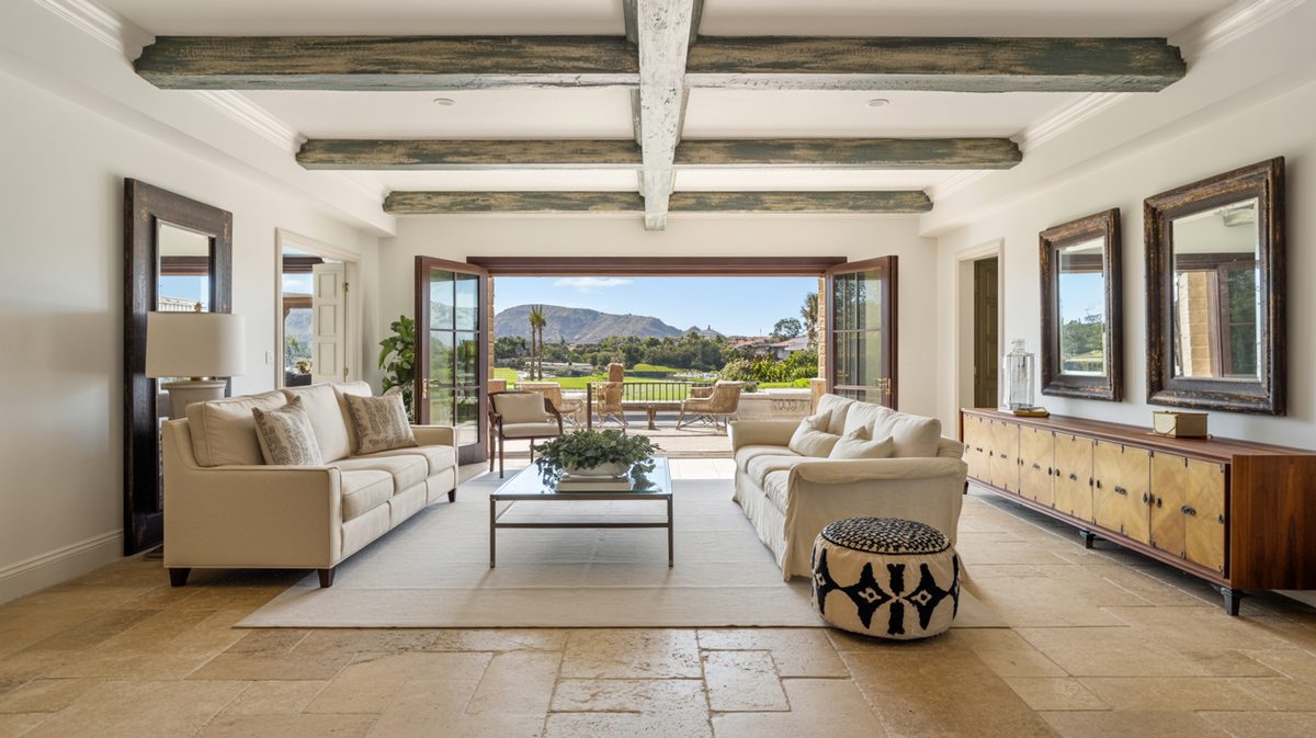 Weathered driftwood style beams across a white ceiling in a lounge with French doors opening to a mountain view