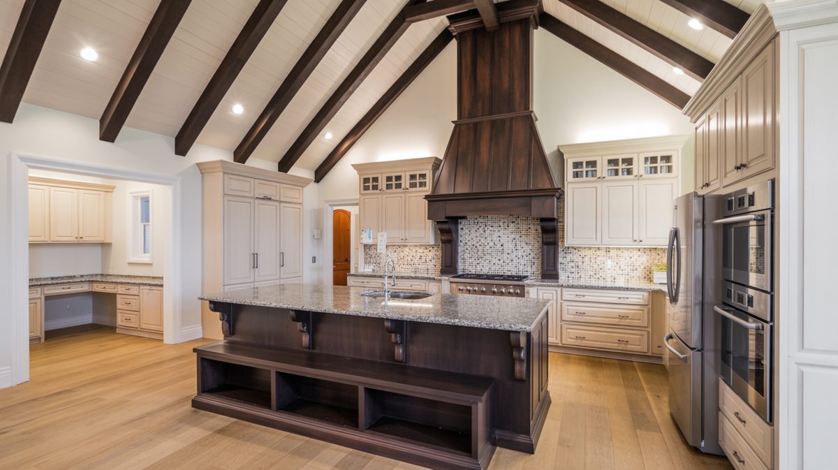 Espresso beams on a vaulted kitchen ceiling with a dark wood range hood and granite topped island with bench