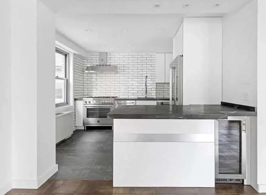 White kitchen with black quartz peninsula and black tile