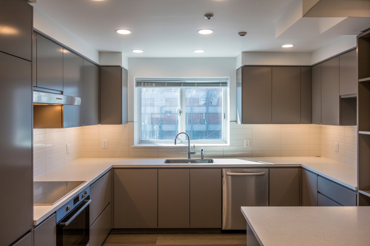 Gray U-shaped kitchen with recessed ceiling lights and a window over the sink