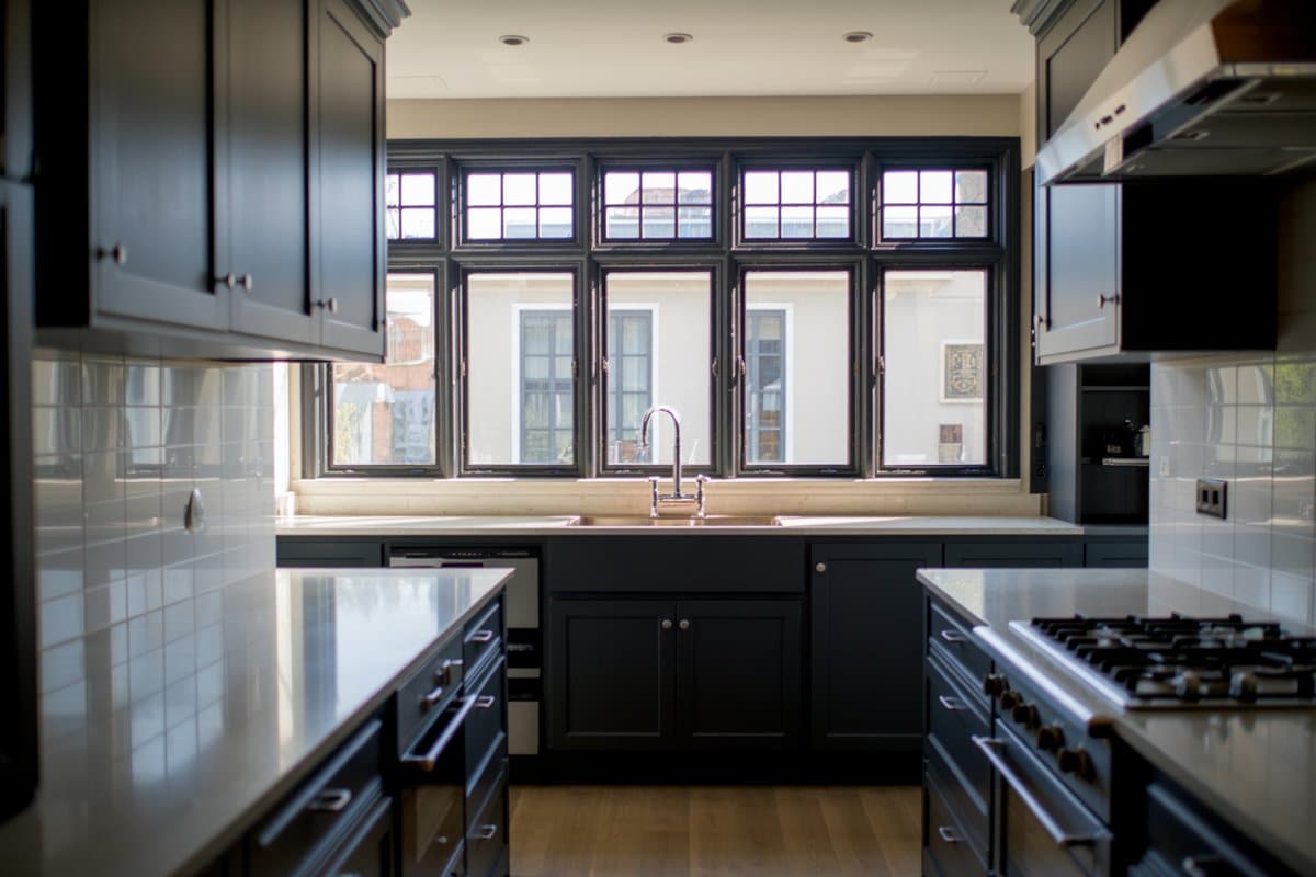 Black colonial grid windows above the sink in a dark galley kitchen