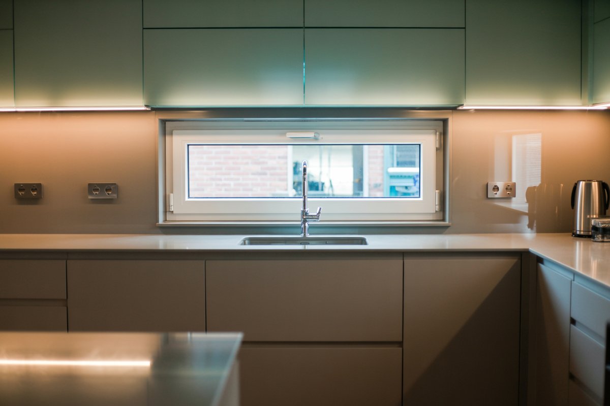 Long sink window with a sill shelf in a green gloss handleless kitchen