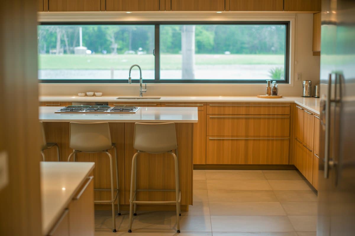 Bamboo kitchen with a wide sink window overlooking a green lawn and trees