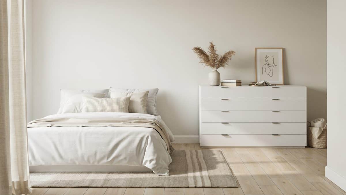 White bedroom with a soft runner beside the bed facing a wide white six drawer dresser