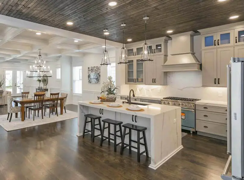beige-kitchen-with-waterfall-quartz-countertop-island-wood-flooring-wood-slat-ceiling