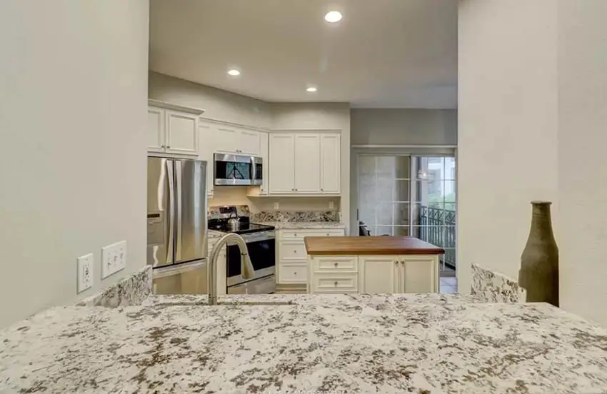 closed-kitchen-with-pass-through-beige-cabinets-granite-countertops