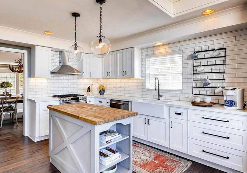 Kitchen with blinds in window, shaker cabinets, tile backsplash and butcher block island