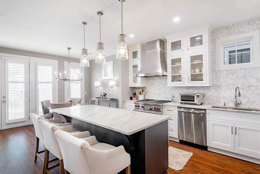 Kitchen with stainless steel oven hood, white cabinets and quartz counters