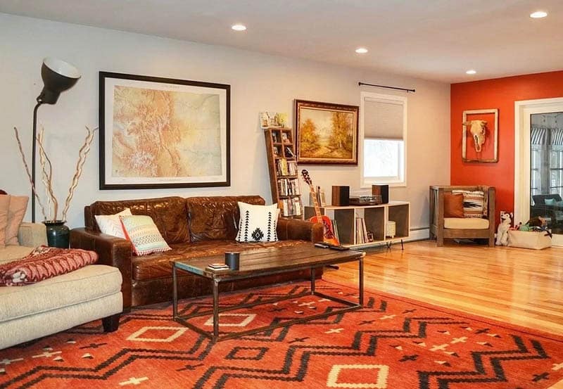 Living room with brown sofa orange accent wall orange rug