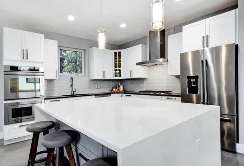 White kitchen with small window, gray backsplash and pendant downlights above island