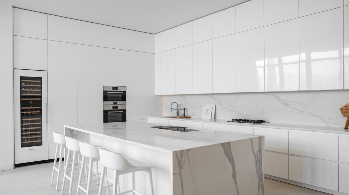 All-white minimalist kitchen with Carrara marble waterfall island and built-in wine fridge