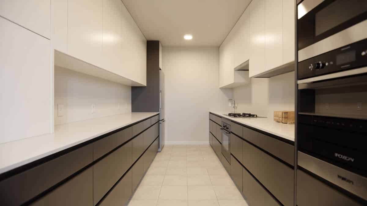 Narrow galley kitchen with white upper cabinets and black lower cabinets