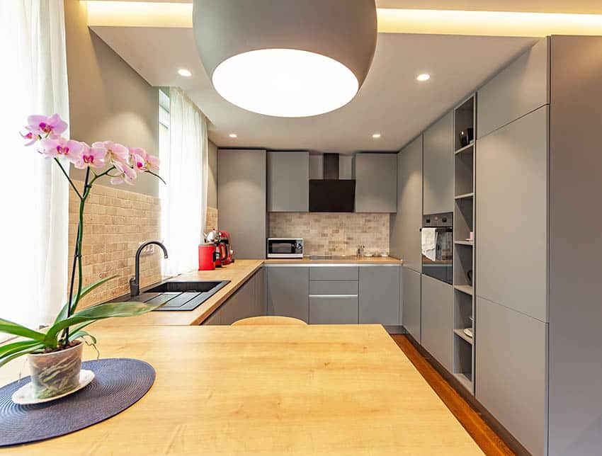 Closed kitchen design with grey cabinets and small peninsula