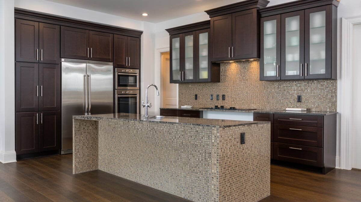 Dark espresso kitchen with island wrapped in mosaic tile panels and frosted glass upper cabinets