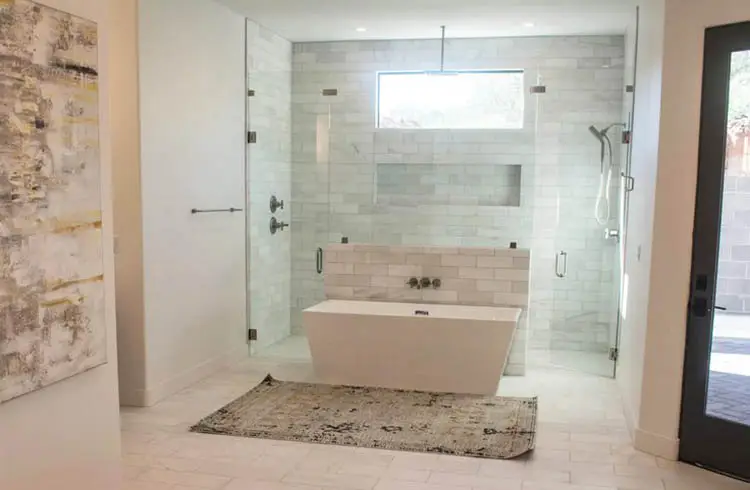 White bath tub beside an enclosed shower area with glass partitions