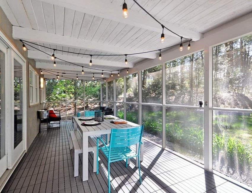 Enclosed screen patio with white plank ceiling string lights and dining furniture