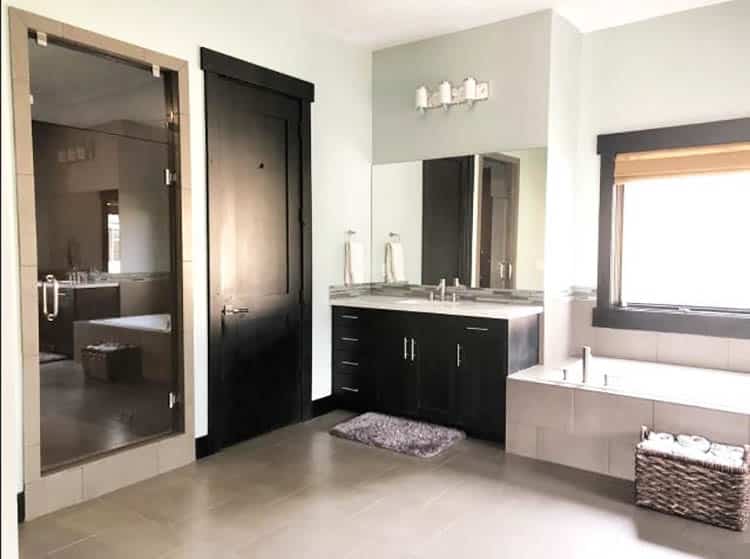 Bathroom with vanity countertop and black cabinets, floor-length mirror and alcove tub
